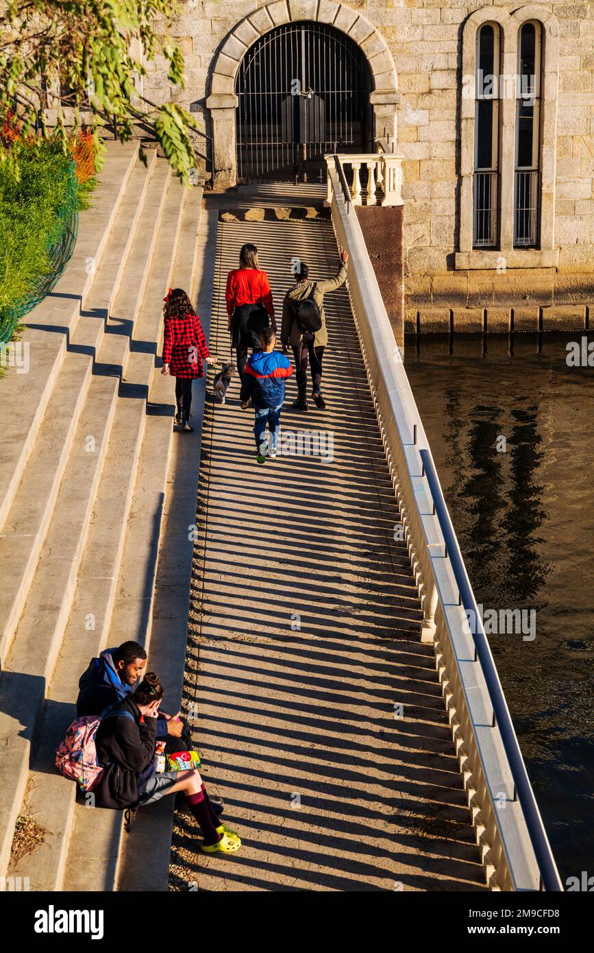 I visitatori che camminano felicemente lungo il sentiero in pietra illuminato dal sole; Fairmount Water Works; Schuylkill River; Philadelphia; Pennsylvania; STATI UNITI Foto Stock