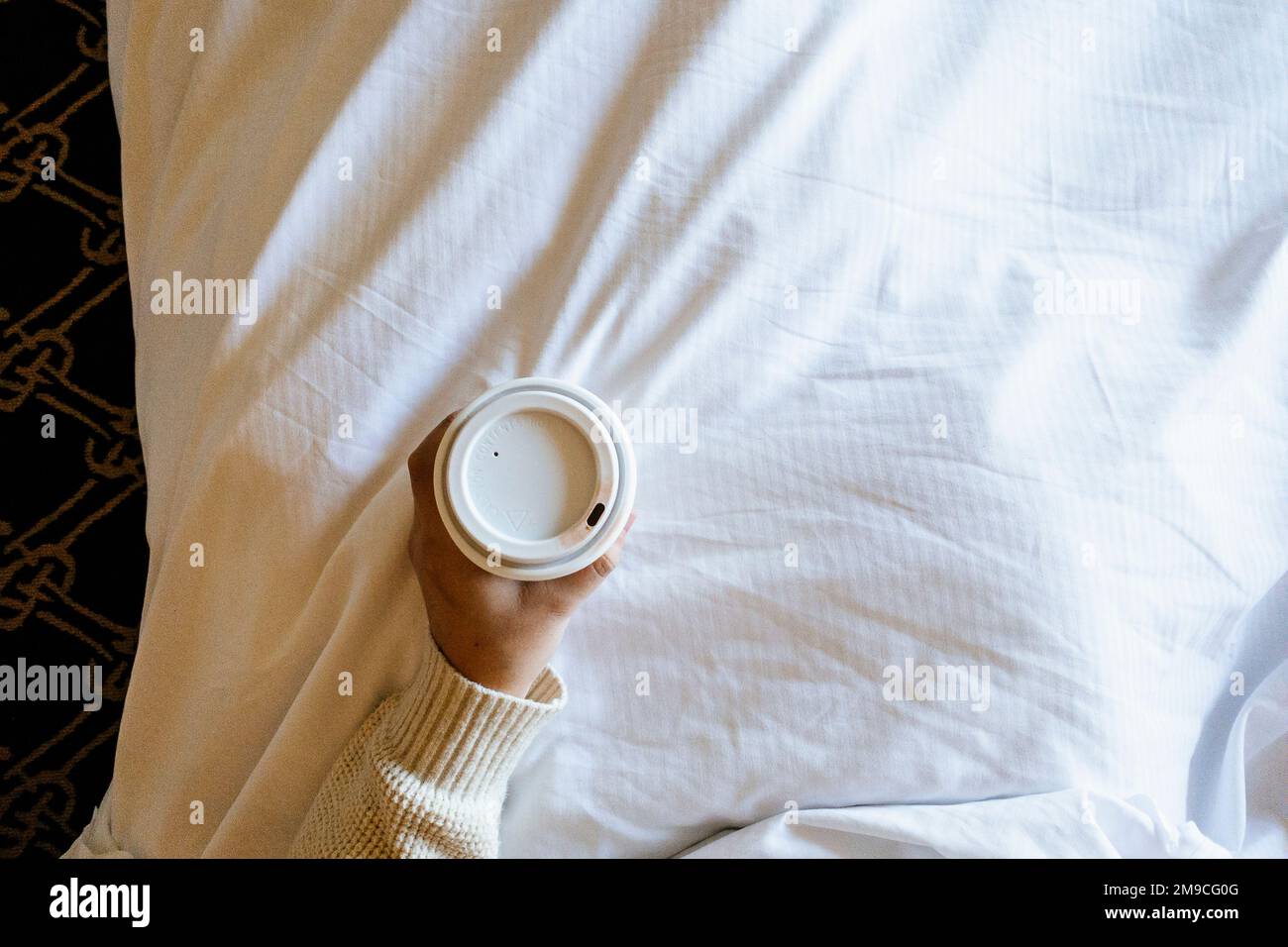 Donna che tiene la tazza di carta di caffè nel letto con il Lipstick Foto Stock