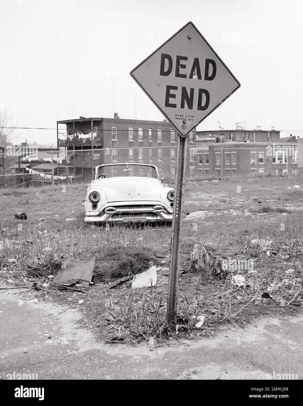 1960S ANGOLO LOTTO LIBERO CON AUTO ABBANDONATA CUCCIOLATA VICOLO CIECO SEGNALE URBANO BLIGHT BASSO REDDITO PROGETTO DI ALLOGGIO IN BACKGROUND - S14389 HAR001 HARS LOTTO TRISTEZZA DISASTRO SPAZZATURA PROPRIETÀ ESTERNO DISPERAZIONE ABBANDONATO UMORE REDDITO IMMOBILIARE CONCETTUALE GLUM STRUTTURE LETTER RELITTO EDIFICIO BLIGHT VACANTE BASSO MISERABILE TRASCURATO PROGETTO DURO NERO E BIANCO DECLINO HAR001 SENZA SPERANZA VECCHIO STILE Foto Stock