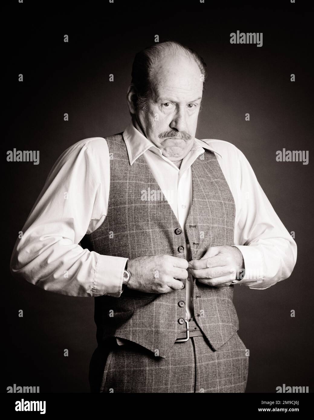 1980S UOMO BALDANTE DI MEZZA ETÀ CON MUSTACHE CHE GUARDA LA TELECAMERA SUCCHIANDOLA MENTRE CERCA DI BUTTARE IL SUO GILET ATTRAVERSO IL SUO MEDIO - S21763 TEU001 HARS HOME VITA COPIA SPAZIO METÀ LUNGHEZZA FISICA FITNESS PERSONE MASCHI UOMO ANZIANO GIUBBOTTO ADULTO ESPRESSIONI TRAVAGLIATO MEDIO-VECCHIO B & W INTERESSATO TRISTEZZA OCCHIO OBIETTIVI DI CONTATTO MUSTACHE DIMENSIONE VECCHIO ETÀ OLDSTERS OLDSTER AVVENTURA IL SUO BALDING FRUSTRAZIONE CERCANDO UMORE GLI ANZIANI IMBARAZZATI GUADAGNO GLUM ATTRAVERSO SUCKING DIFFICOLTÀ CRESCITA MISERABILE TROPPO PICCOLO, MENTRE NERO E BIANCO ETNICITÀ CAUCASICA VECCHIO STILE Foto Stock