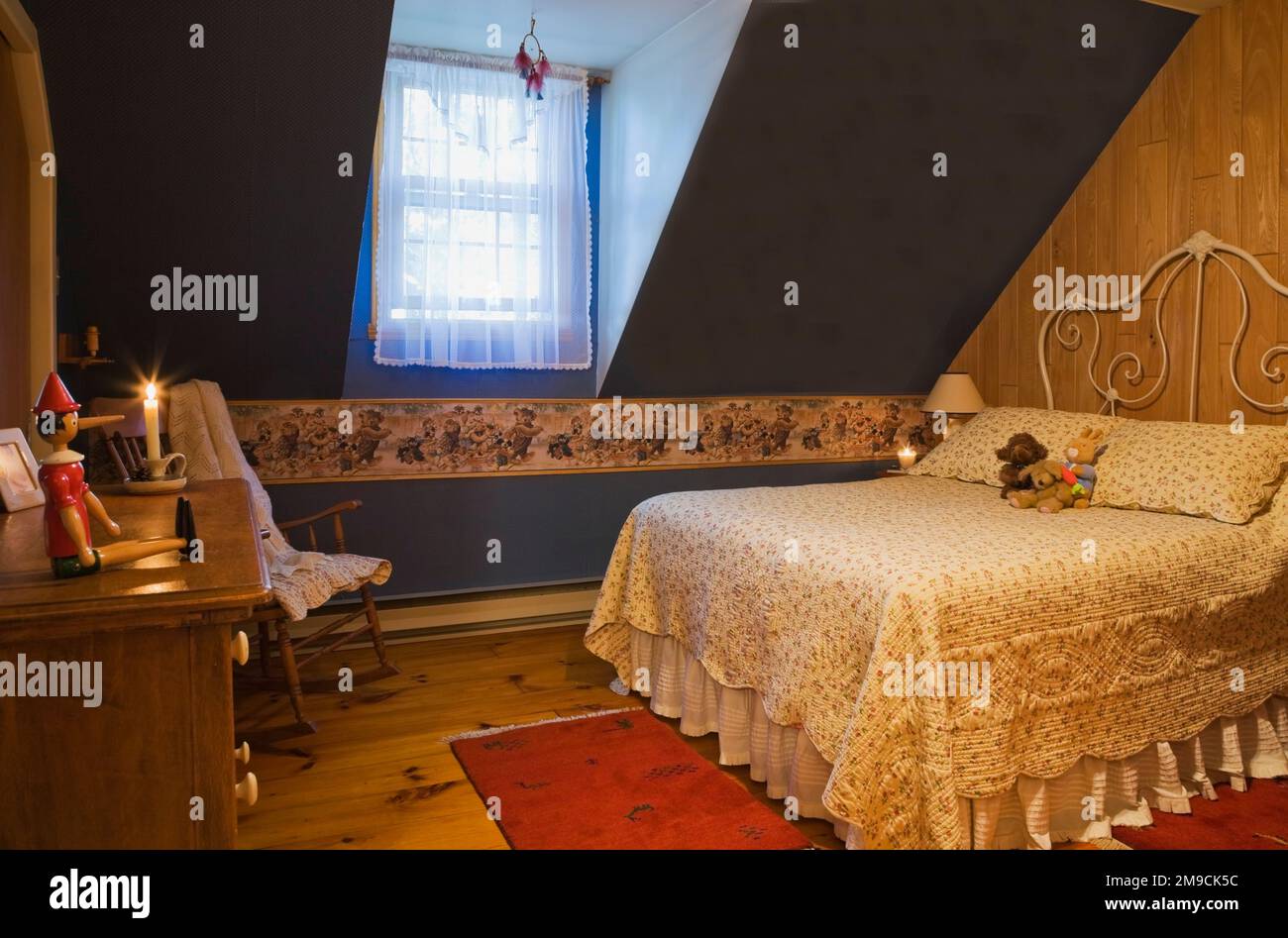 Camera da letto con vecchio letto queen size al piano superiore all'interno di una casa in legno in stile canadese. Foto Stock