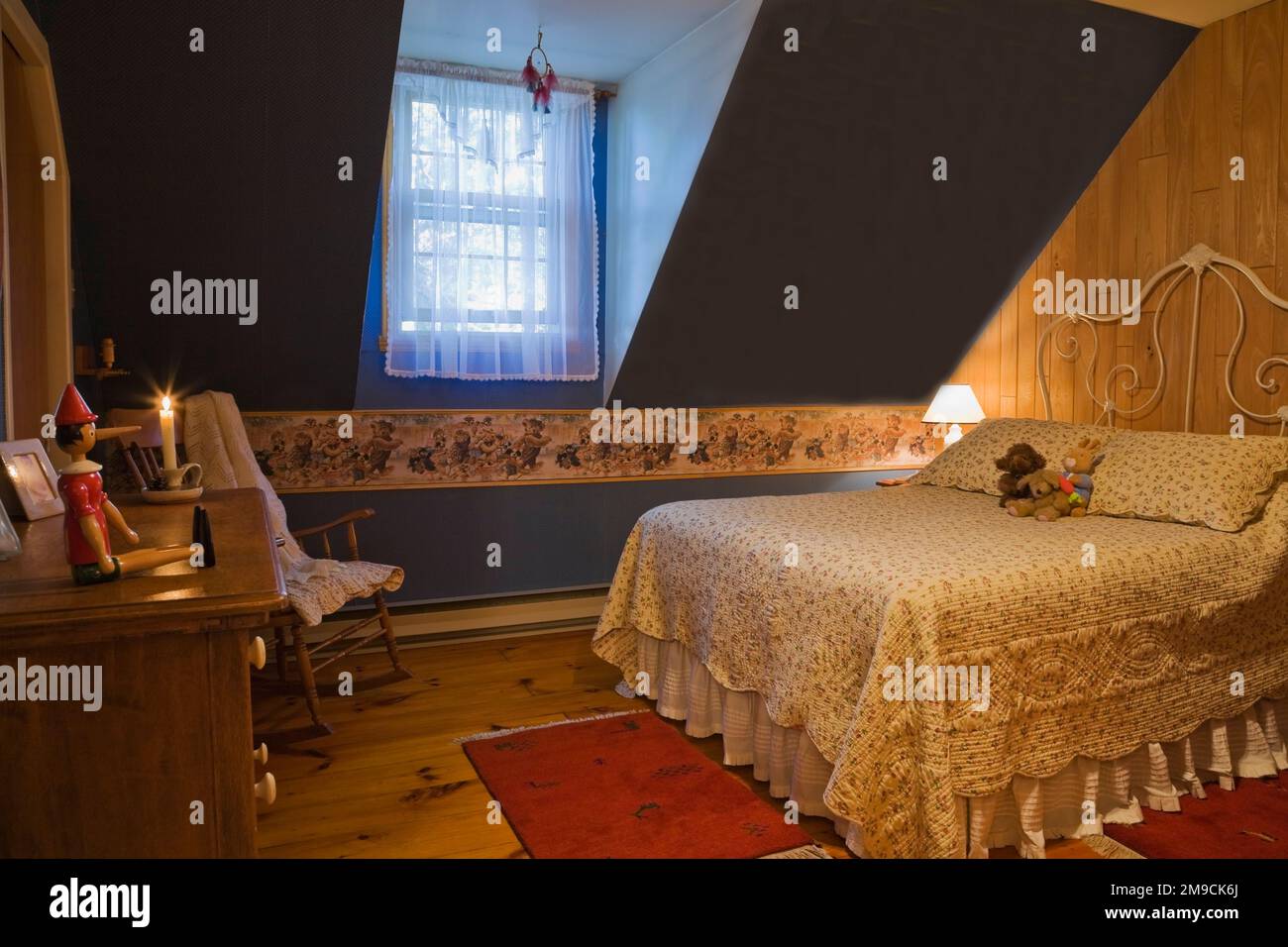 Camera da letto con vecchio letto queen size al piano superiore all'interno di una casa in legno in stile canadese. Foto Stock