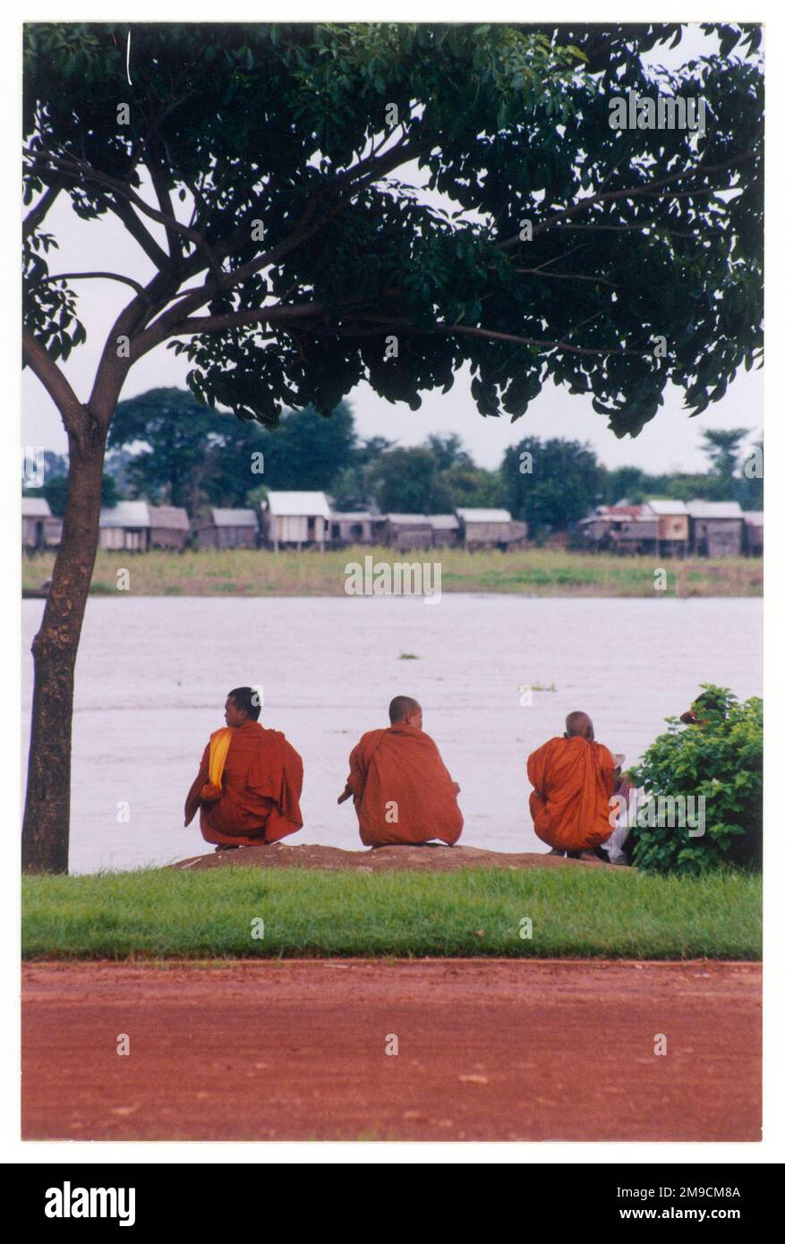 Tre monaci contemplativi sulla riva del fiume a Phnom Penh, Cambogia. Foto Stock