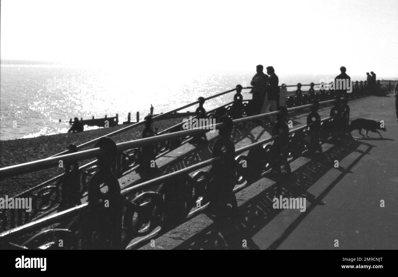 Le ringhiere al lungomare di Brighton, la spiaggia e la luce del tardo pomeriggio sul mare Foto Stock