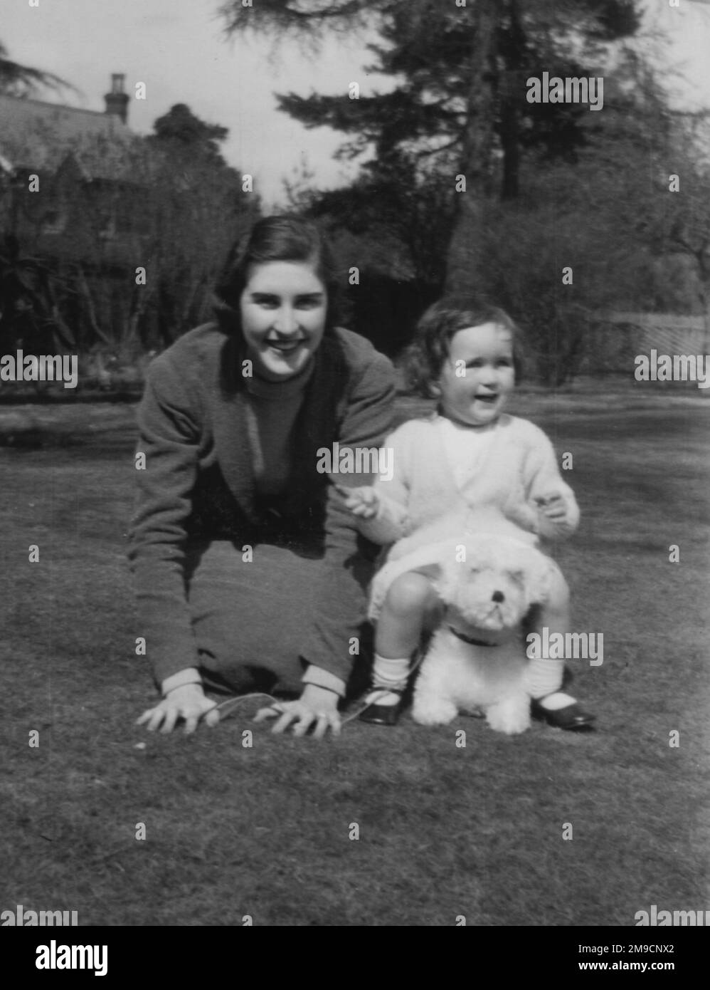 Due sorelle mezze giocano sul prato con un cane giocattolo, in un giardino a Fleet, Hampshire. Foto Stock