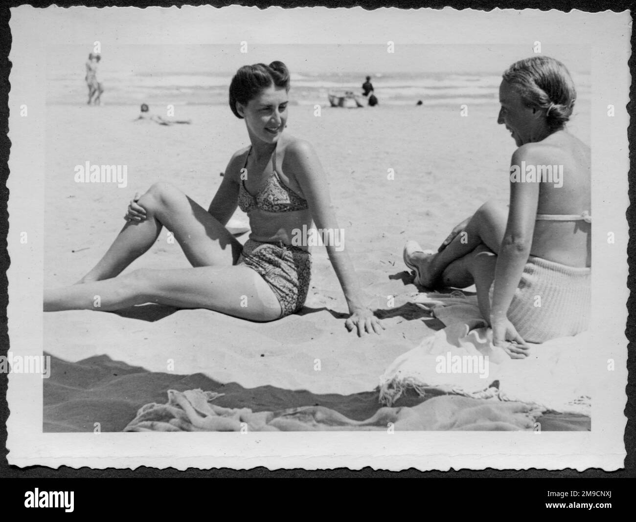 Due giovani amiche si siedono in costume da bagno su una spiaggia in Italia. Foto Stock
