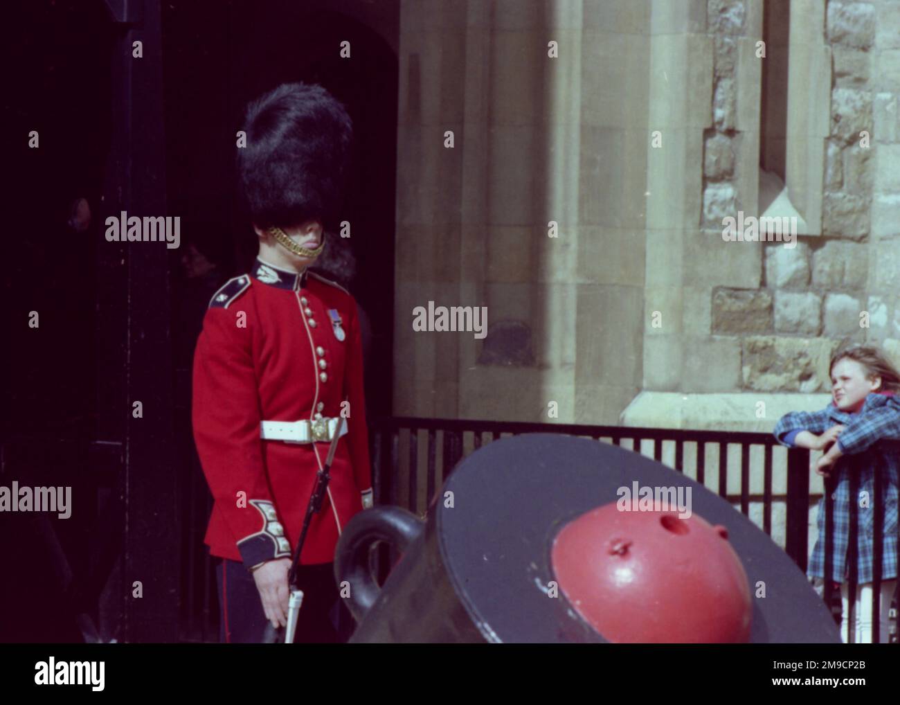 Un guardiano nella sua distintiva uniforme rossa e cappello di bearskin sta in guardia alla Torre di Londra. Foto Stock