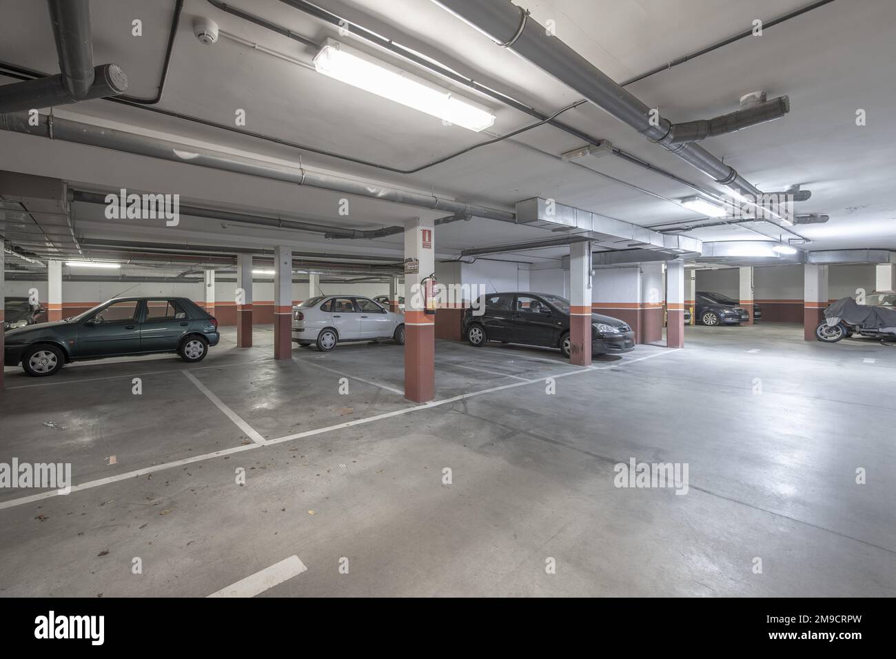 Piano terra di un edificio dedicato ad un garage con pavimento in cemento e spazi segnati con vernice bianca Foto Stock