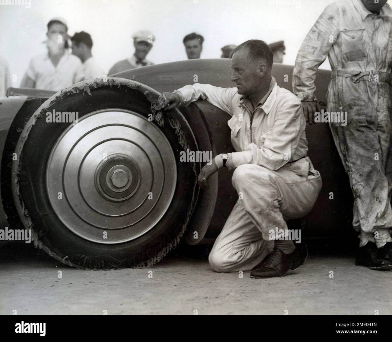 Malcolm Campbell in piedi da un pneumatico trinciato con meccanici e altre figure. Foto Stock