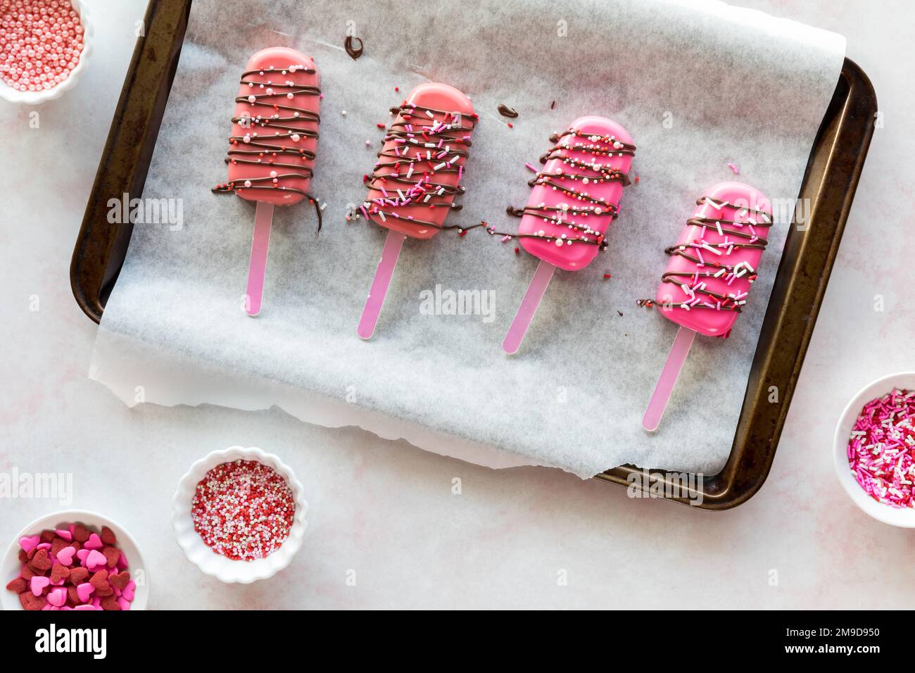 Cakesicles fatti in casa, cosparsi di melt caramelle e decorate con spruzzi. Foto Stock