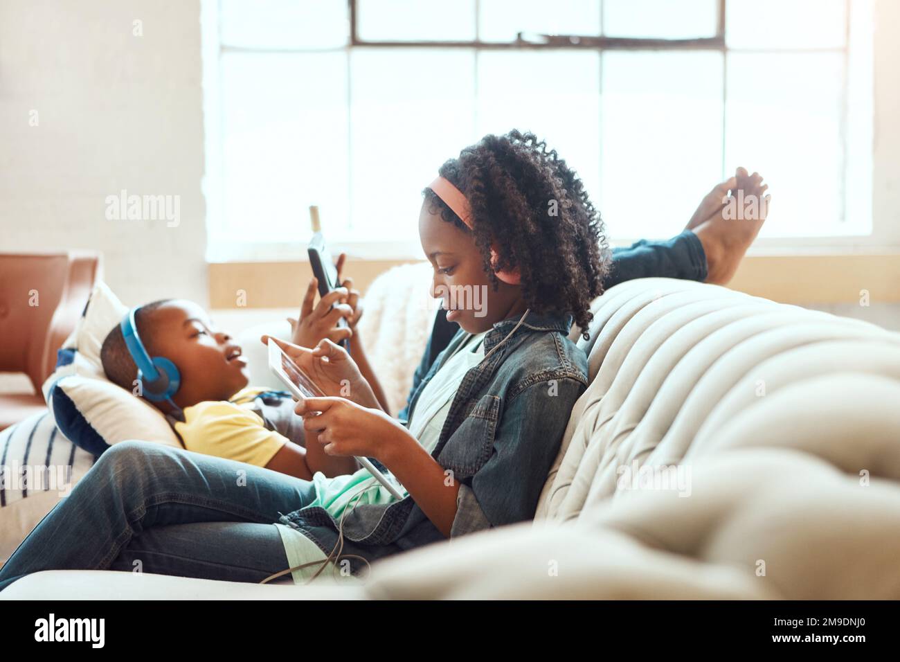 Telefono, famiglia e sorella fratello rilassarsi su un divano, online e home entertainment mentre si siede in una sala. Internet, fratelli e ragazza con ragazzo su un Foto Stock