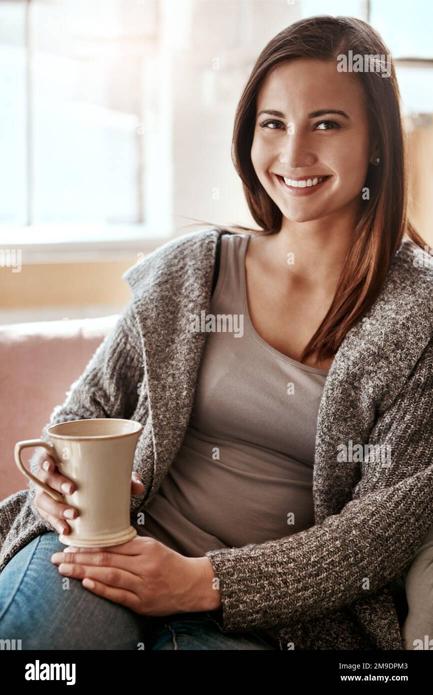 Sorriso, donna e caffè ritratto a casa su un divano soggiorno sensazione di calma e relax. Casa, tè e la felicità mattutina di una persona con un drink su un Foto Stock