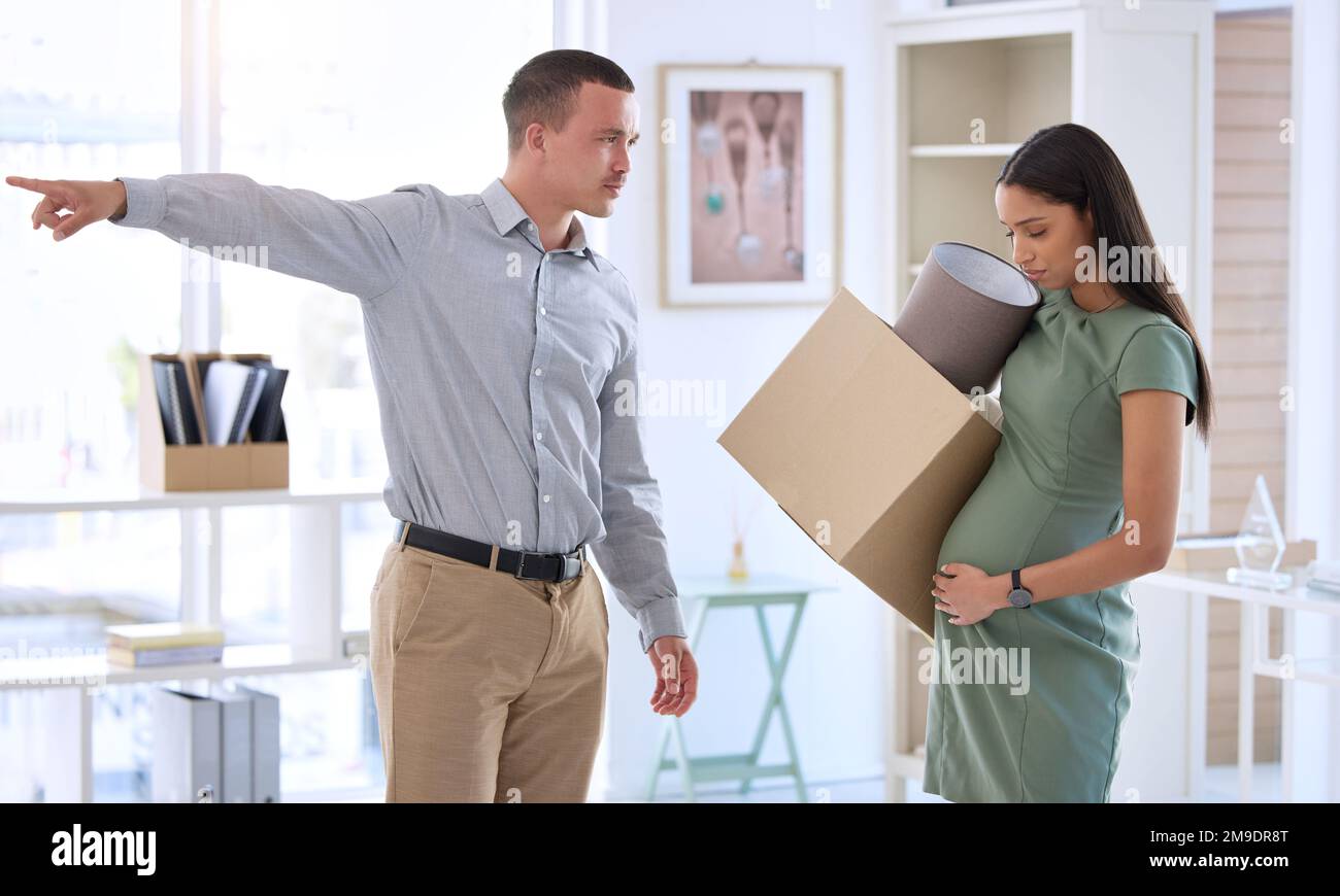 Uscire. un bel giovane uomo d'affari in piedi in ufficio e licenziare la sua lavoratrice incinta. Foto Stock