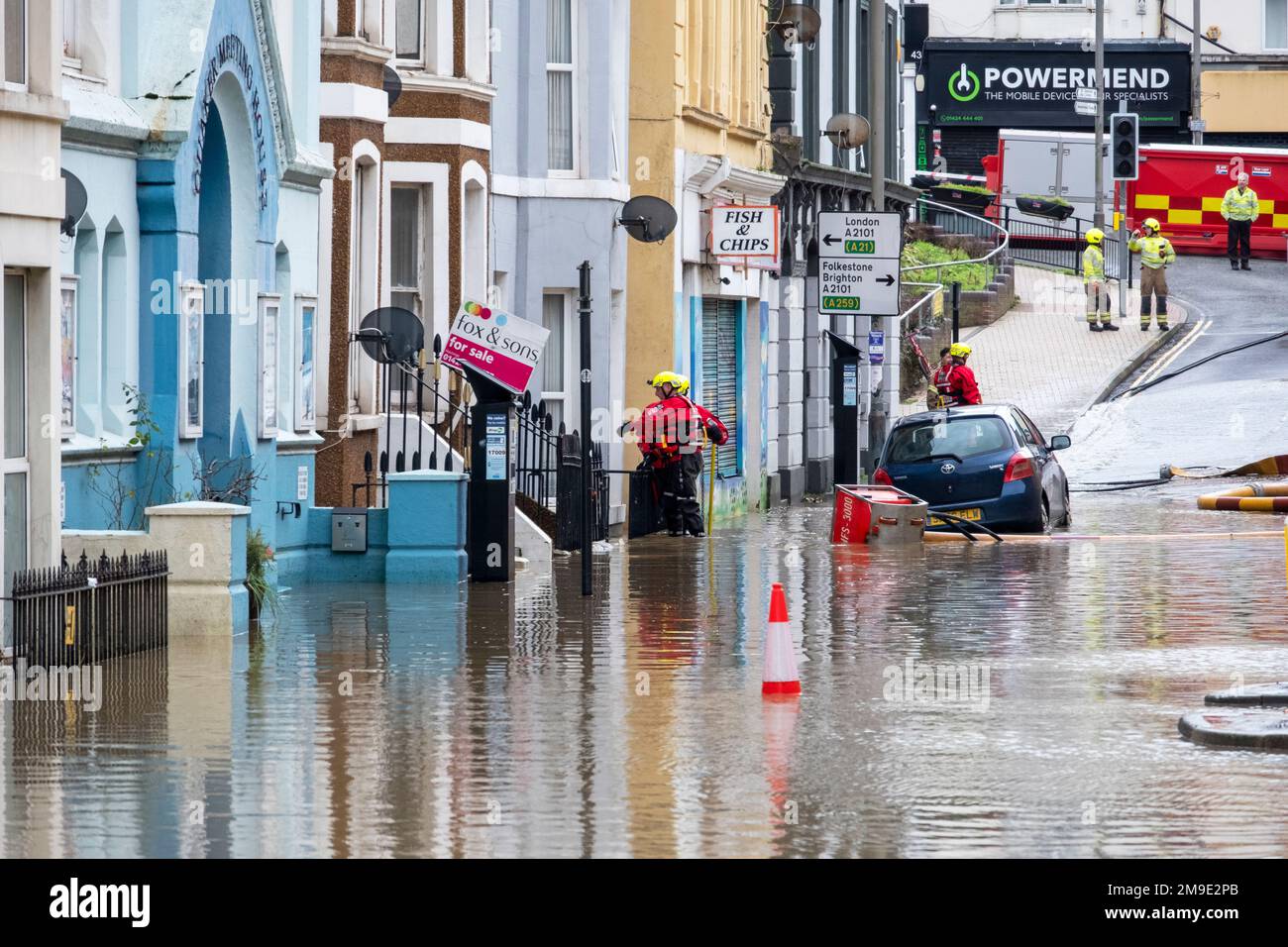 I vigili del fuoco pompano acqua allagata dalle case e dalle aziende dopo che la pioggia pesante causa l'inondazione nella città di Hastings e chiude il centro commerciale Priory Meadow Foto Stock