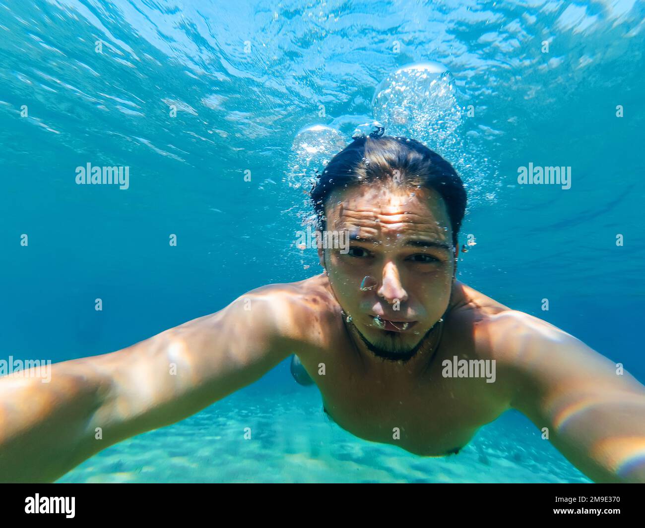 giovane subacqueo maschile nuota in mare nell'acqua blu e fa un selfie del tuo viso Foto Stock