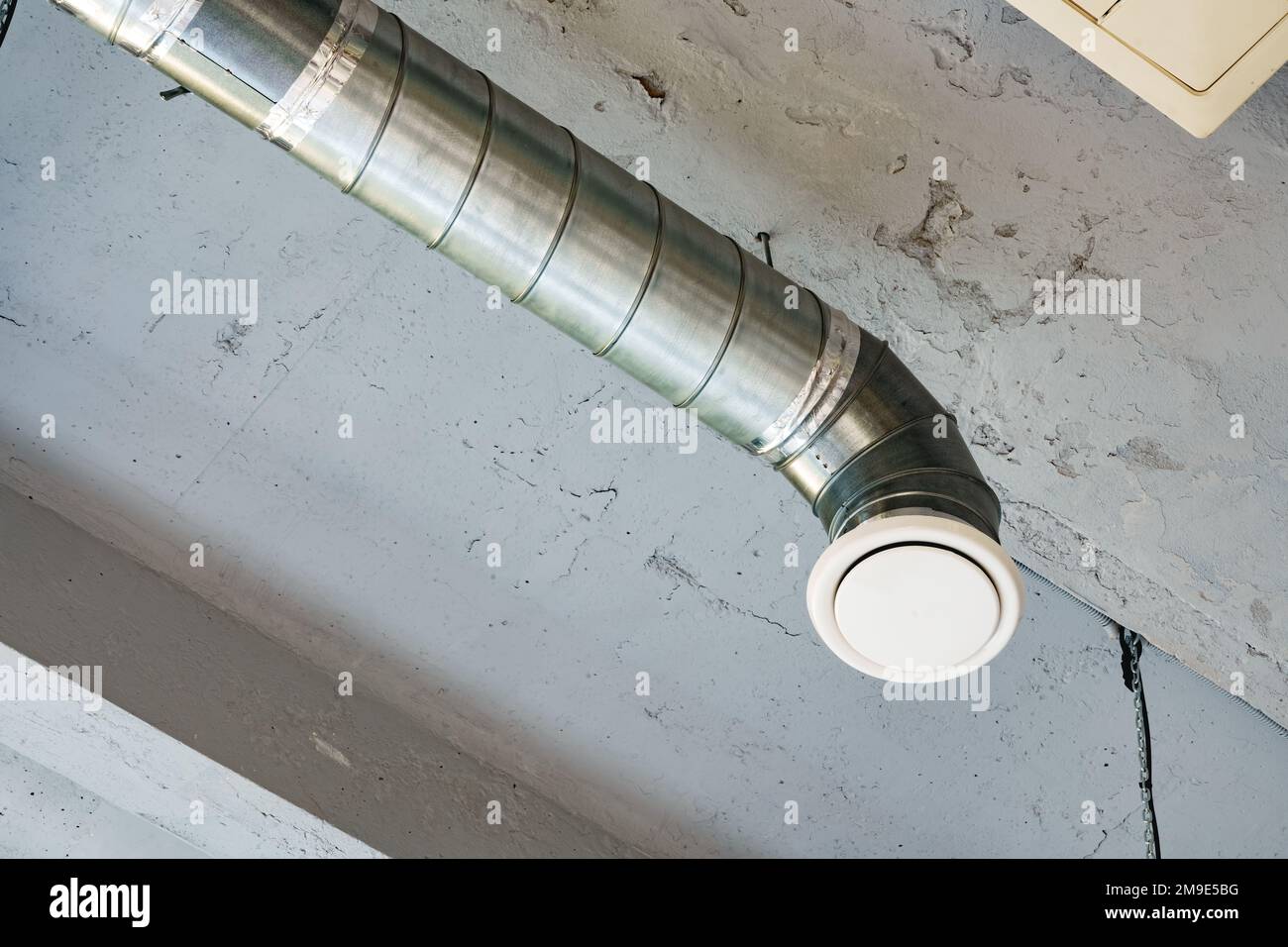 Tubi di ventilazione in argento appesi al soffitto all'interno dell'edificio Foto Stock