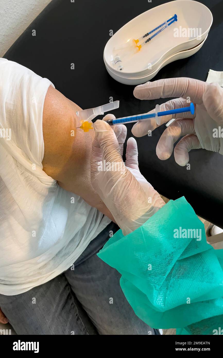 Donna anziana riceve iniezione con siringa medica quarta vaccinazione di richiamo vaccinazione contro la malattia di coronavirus Covid-19 C19 virus corona Foto Stock