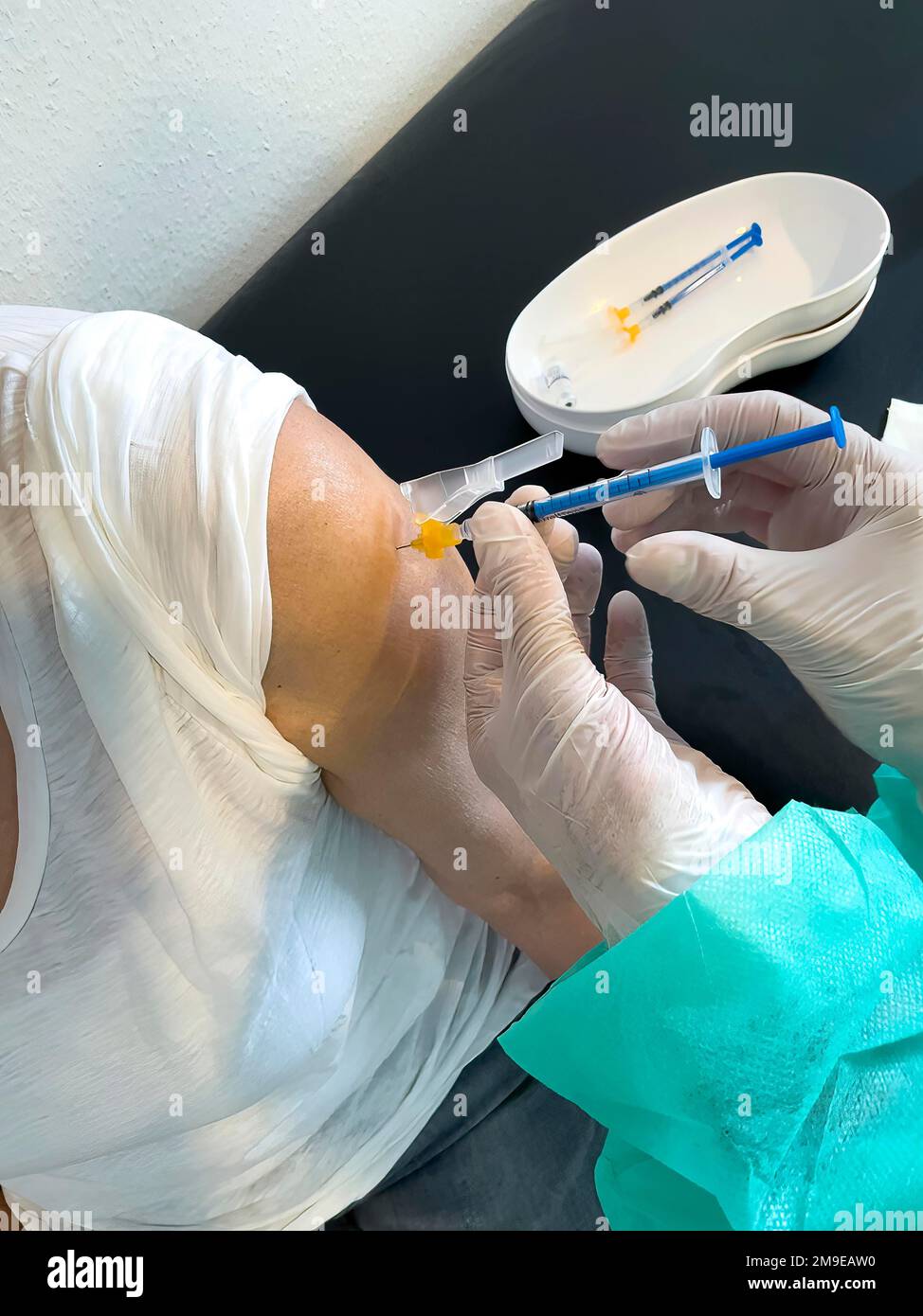 Donna anziana riceve iniezione con siringa medica quarta vaccinazione di richiamo vaccinazione contro la malattia di coronavirus Covid-19 C19 virus corona Foto Stock