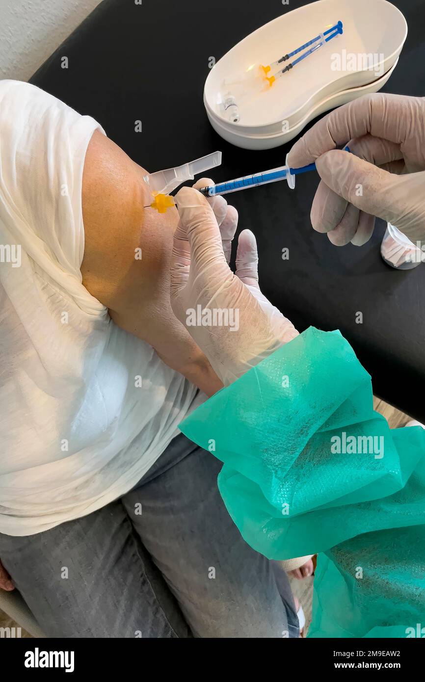 Donna anziana riceve iniezione con siringa medica quarta vaccinazione di richiamo vaccinazione contro la malattia di coronavirus Covid-19 C19 virus corona Foto Stock