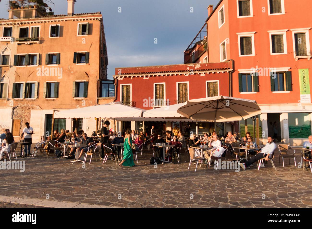 Persone che hanno un drink su una terrazza fuori un ristorante al tramonto a Venezia, Italia Foto Stock
