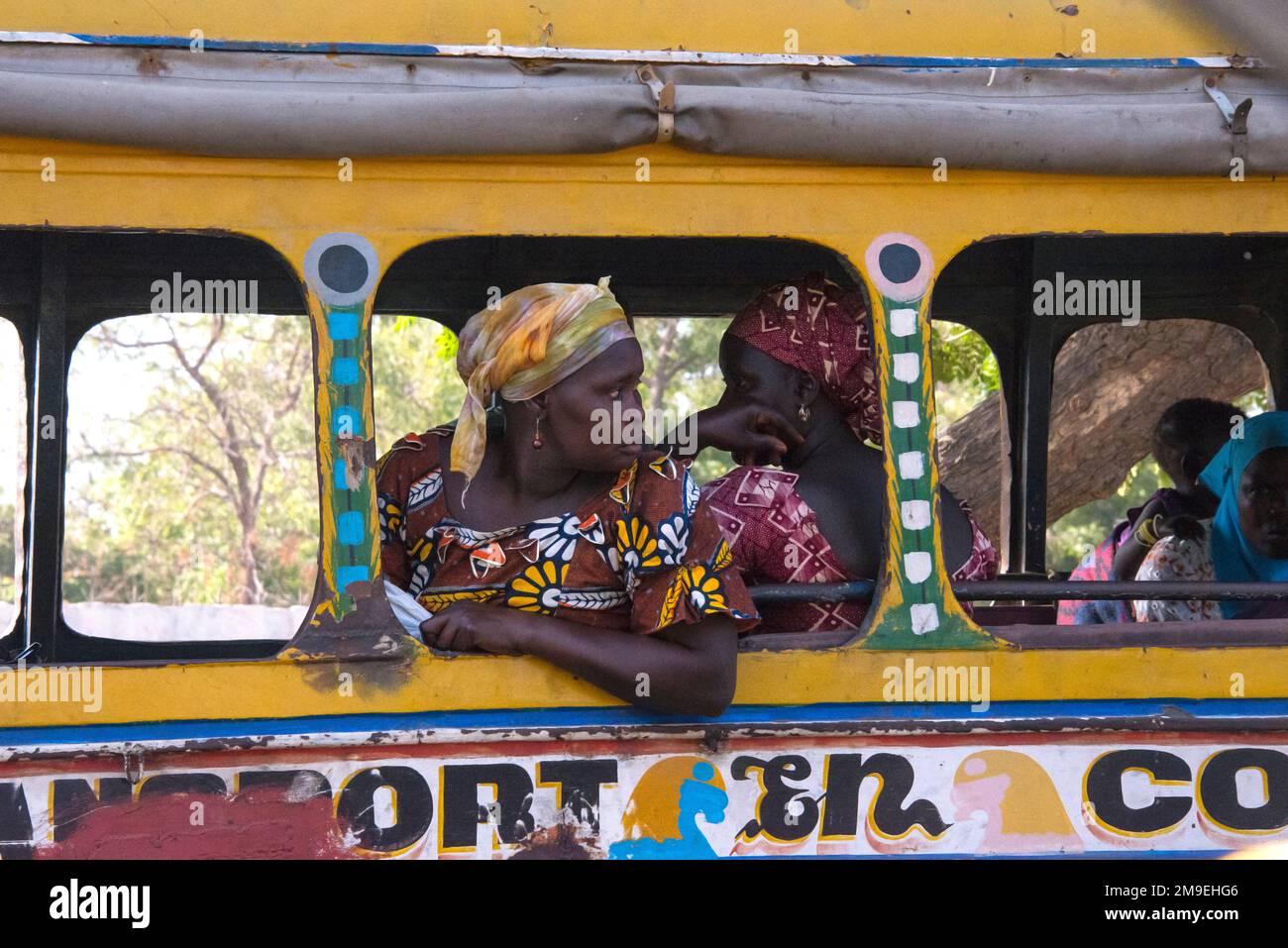 Donne che sporgono dalle finestre di un autobus decorato nella città di Dakar, Senegal Foto Stock