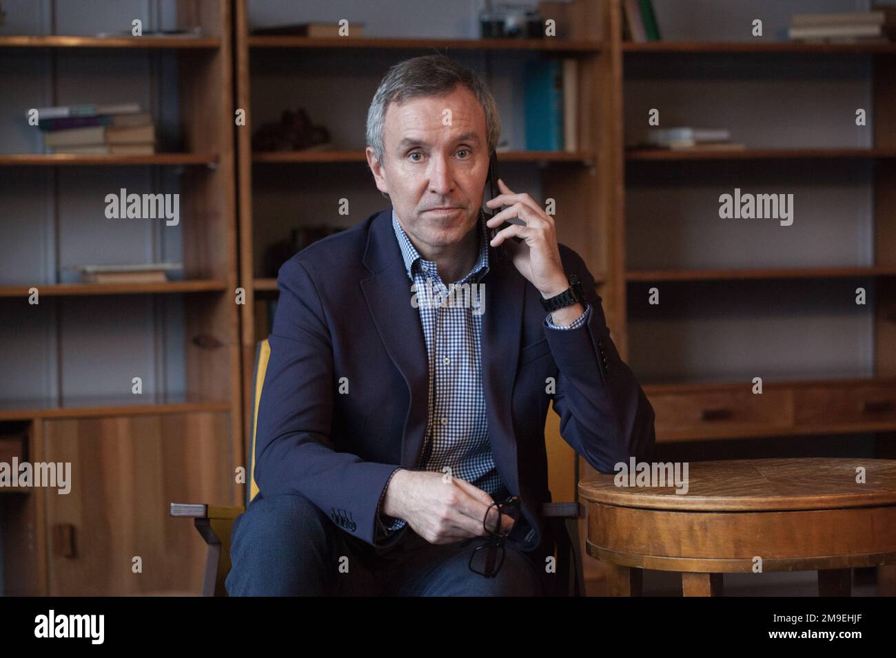 Ritratto di uomo d'affari serio anziano e sicuro in tuta dai capelli grigi parlando di affari con i partner sul suo telefono cellulare Foto Stock