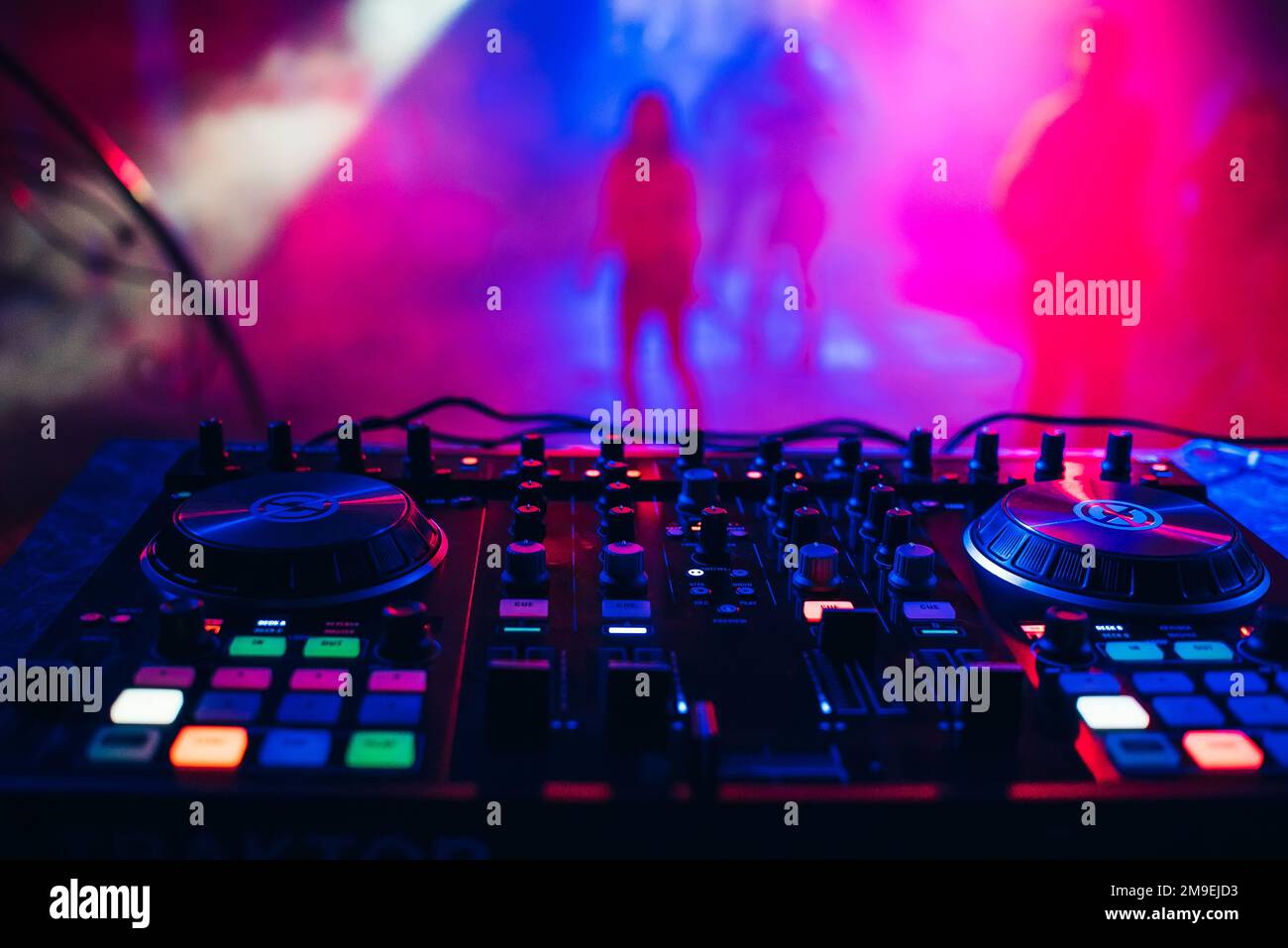 DJ mixer sul sfondo del tavolo il night club e le persone che ballano Foto Stock