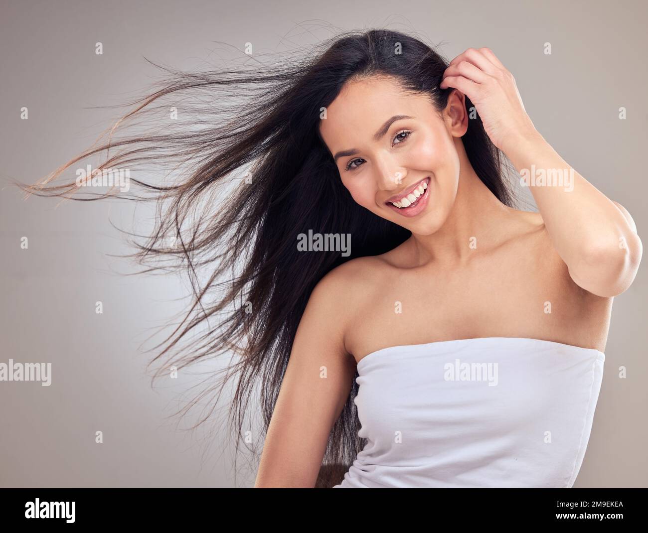 Non sia mai afriad per cambiare la vostra acconciatura. una giovane donna attraente che si posa da sola in studio con i suoi capelli che soffiano nel vento. Foto Stock