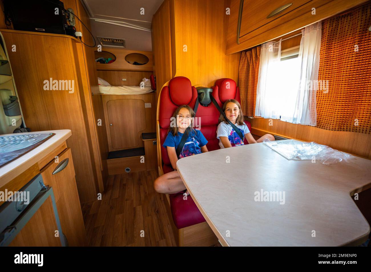 I bambini seduti sui sedili posteriori in camper. L'interno del camper durante la guida in vacanza con la famiglia. Sicurezza dei bambini durante il viaggio. Foto Stock