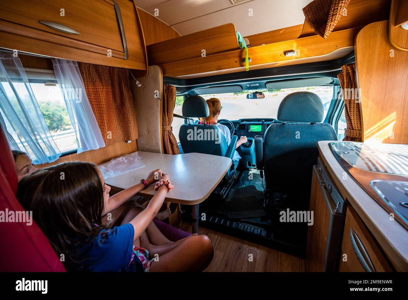 I bambini si sono seduti sui sedili posteriori mentre la madre guida in motonave. L'interno del camper durante la guida in vacanza con la famiglia. Sicurezza dei bambini durante la Foto Stock