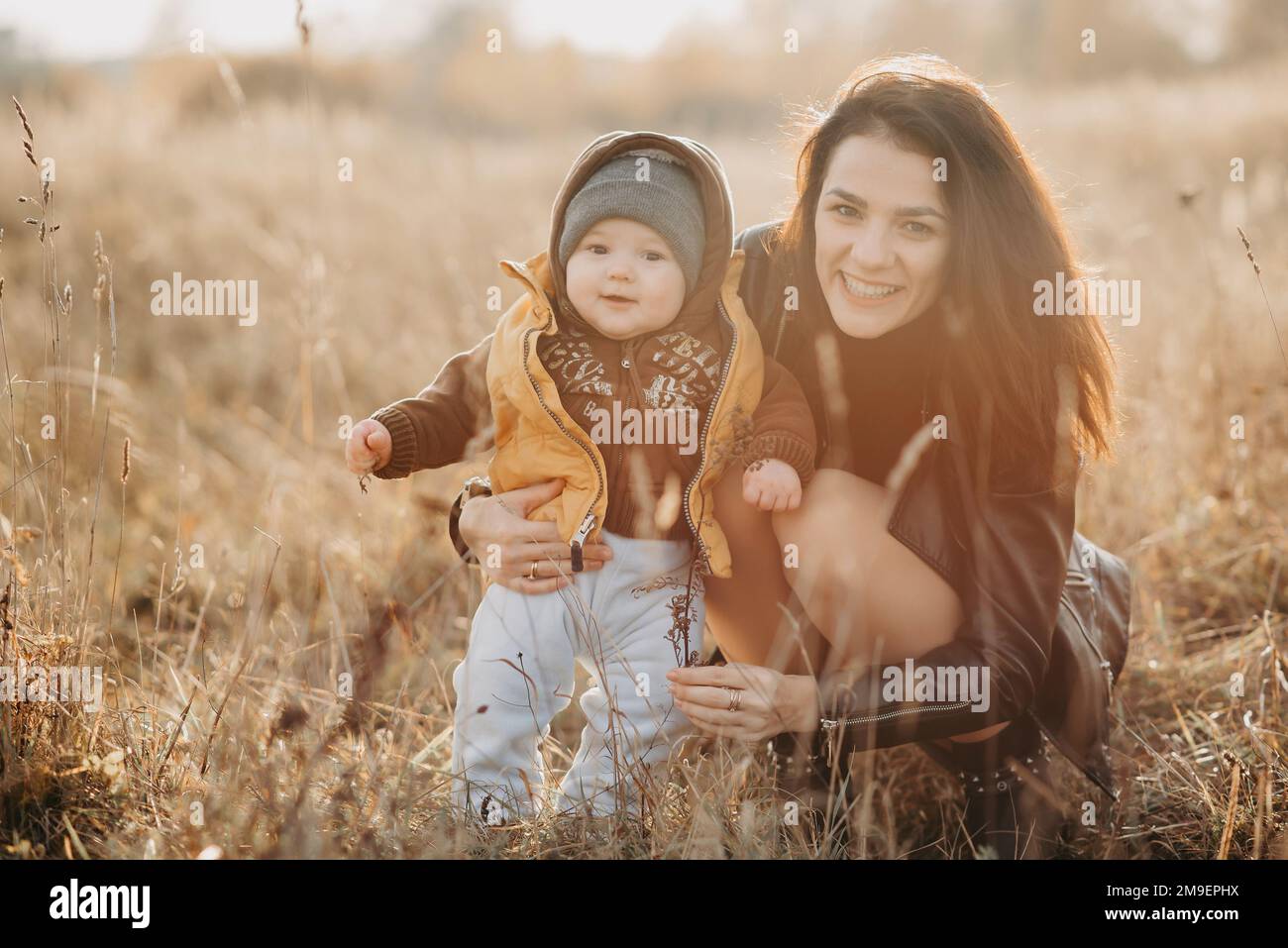 Giovane madre caucasica con un bambino bambino bambino bambino nelle sue mani che si divertono e sorridono in autunno nella natura Foto Stock