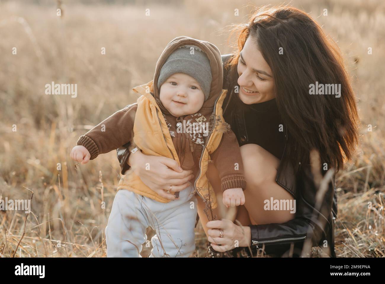 Felice famiglia giovane per una passeggiata in autunno. Mamma con il suo bambino figlio ragazzo all'aperto sorridendo e hanno gioia Foto Stock