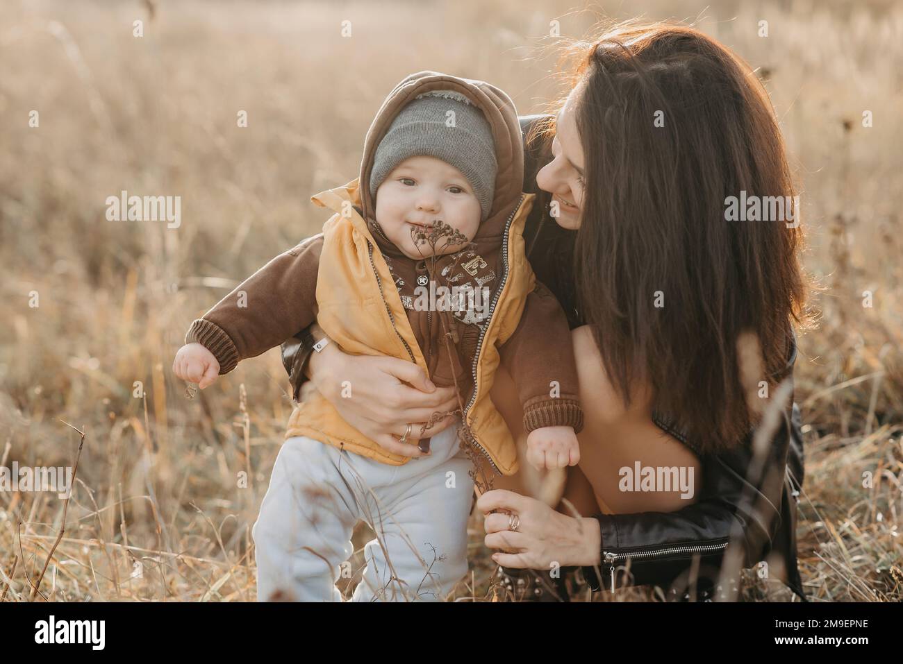 giovane mamma che gioca con il suo bambino figlio in autunno sul campo. Buona passeggiata con la famiglia Foto Stock