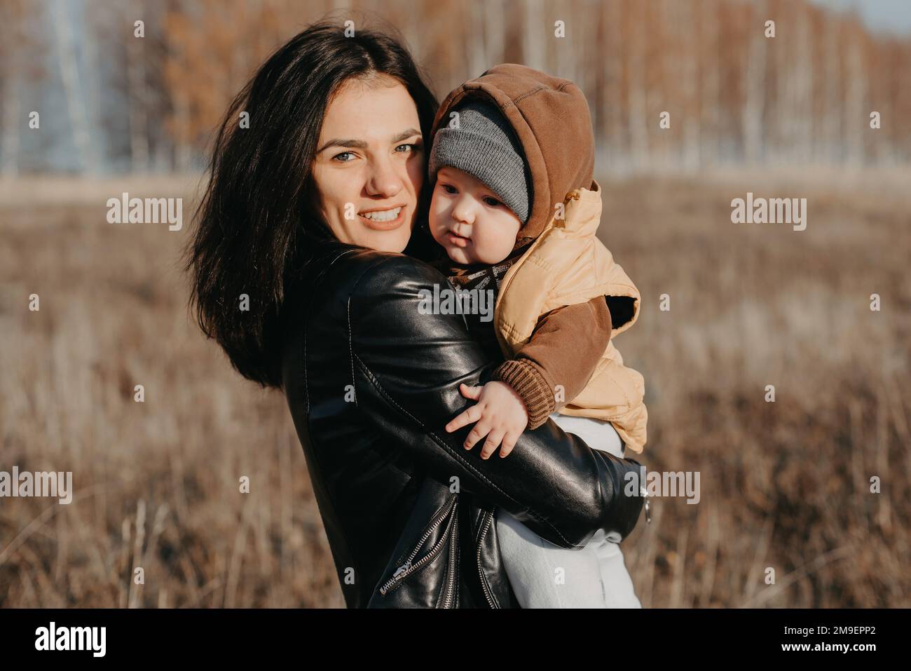 Giovane madre caucasica con un bambino bambino bambino bambino nelle sue mani che si divertono e sorridono in autunno nella natura Foto Stock