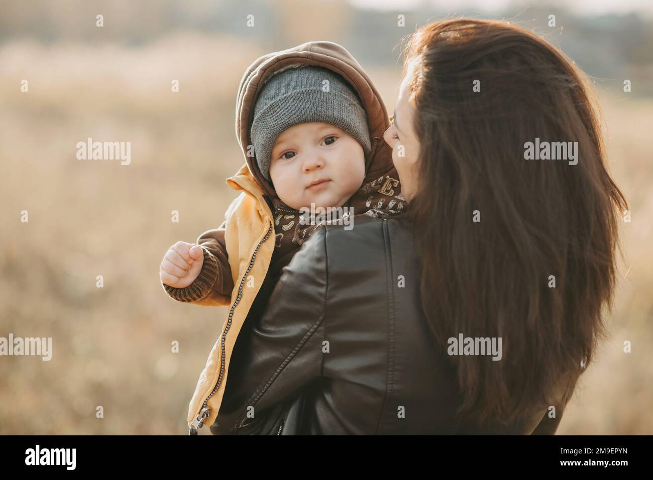 La giovane mamma tiene in braccio il figlio del bambino in autunno sul campo Foto Stock
