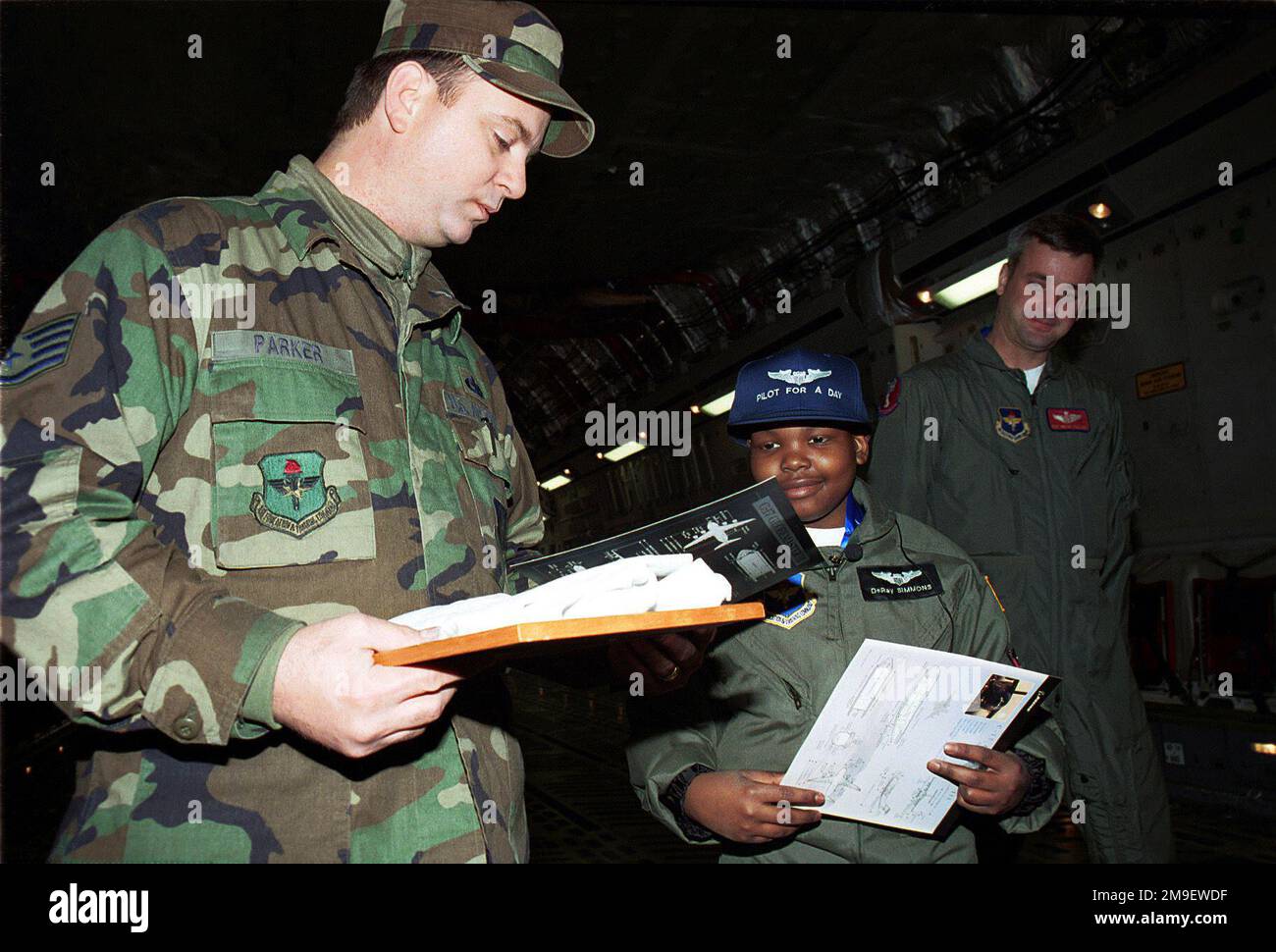 C-17 interno vano di carico, tiro medio, vista frontale destra, Sroff Sergeant Arnold Parks, USAF, 97th manutenzione Squadron, Altus Air Force base, Oklahoma, dà 11 anni paziente di cancro Delray Simmons, il primo bambino selezionato per il programma 'pilota per un giorno', una maglietta squadrone. A guardare è SSGT Brian Williams, USAF, che ha sviluppato il programma "pilota un giorno". Il programma richiede a un individuo un giorno normale per un pilota. Base: Altus Air Force base Stato: Oklahoma (OK) Paese: Stati Uniti d'America (USA) Foto Stock