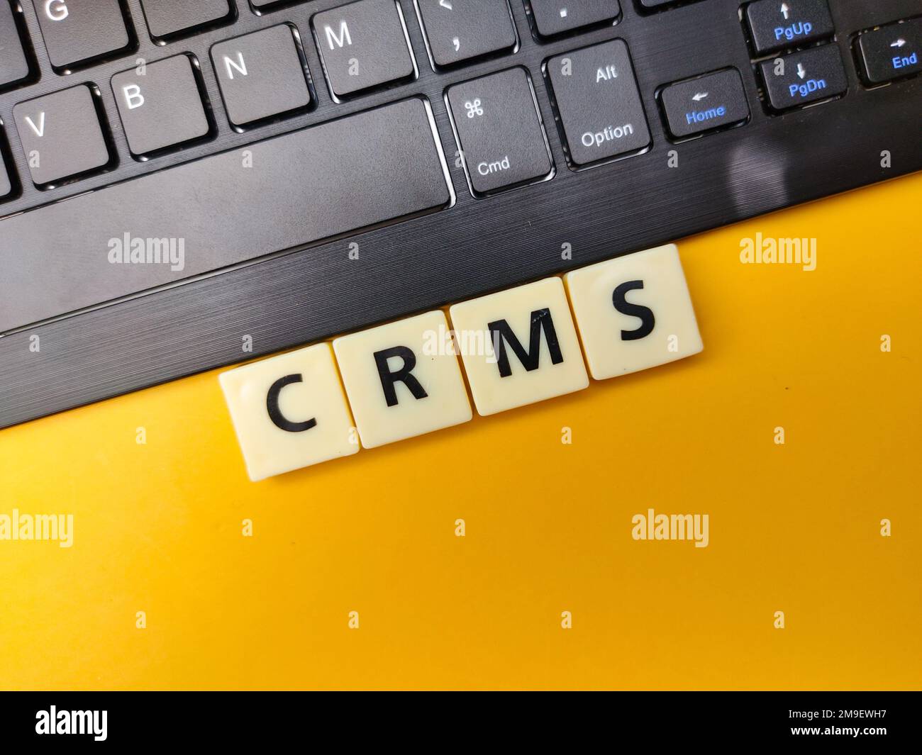 Tastiera nera e giocattoli parola con la parola CRMS su sfondo giallo. Foto Stock