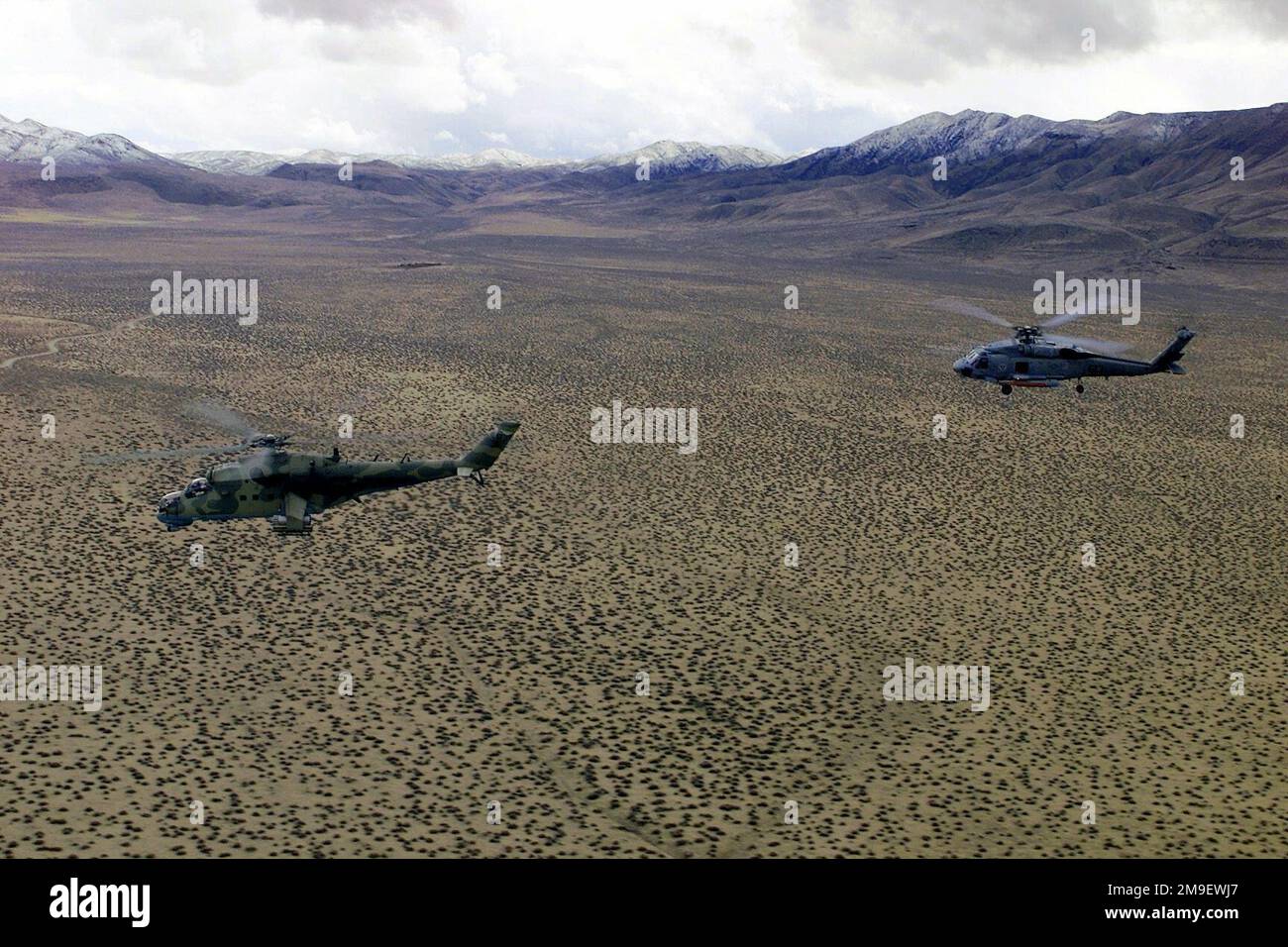 Profilo sinistro ripresa aerea lunga come elicottero Hind mi-24 russo del Centro di Valutazione e Test dell'Esercito, Threat Support Activity, Las Vegas, Nevada (a sinistra), vola in formazione con un elicottero US Navy HH-60 Seahawk, assegnato all'elicottero Anti-Submarine Squadron-Wing Pacific. Desert Rescue è la prima formazione di Ricerca e salvataggio condotta presso la catena di Fallon Naval Air Station, Nevada. Soggetto operativo/Serie: BASE DI SALVATAGGIO NEL DESERTO: Base aerea navale, Fallon Stato: Nevada (NV) Paese: Stati Uniti d'America (USA) Foto Stock