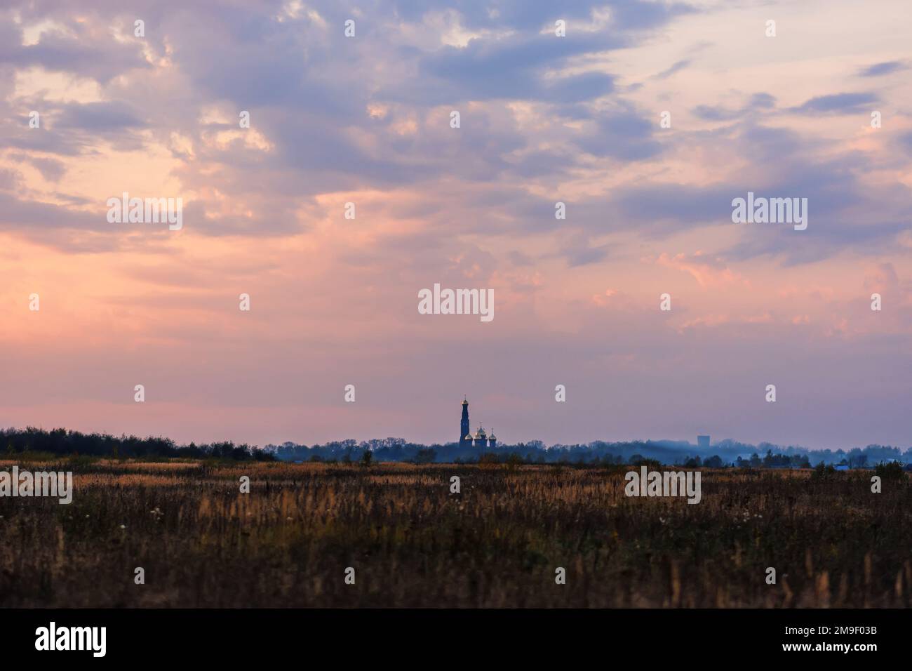 Paesaggio con la Chiesa Ortodossa all'orizzonte nella sera d'autunno con un bel cielo Foto Stock