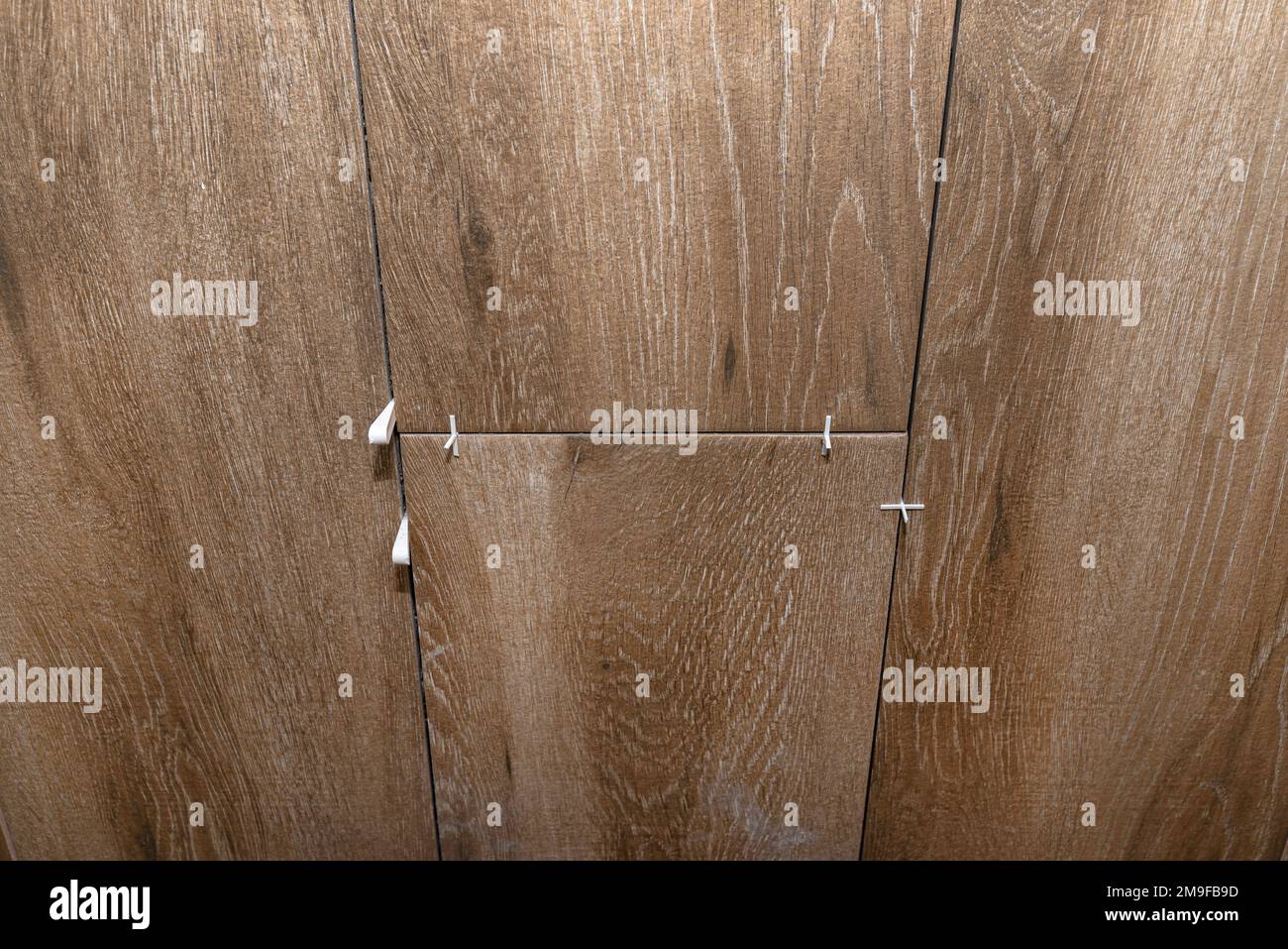 Distanziatori in plastica e distanze per la posa di piastrelle in ceramica, piastrelle che imitano il legno. Foto Stock