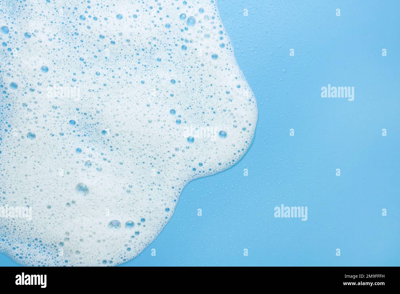 Schiuma bianca, mousse su sfondo blu. Bordo per il testo espanso. Il concetto di prodotti schiumogeni, cosmetici o detergenti. Foto Stock