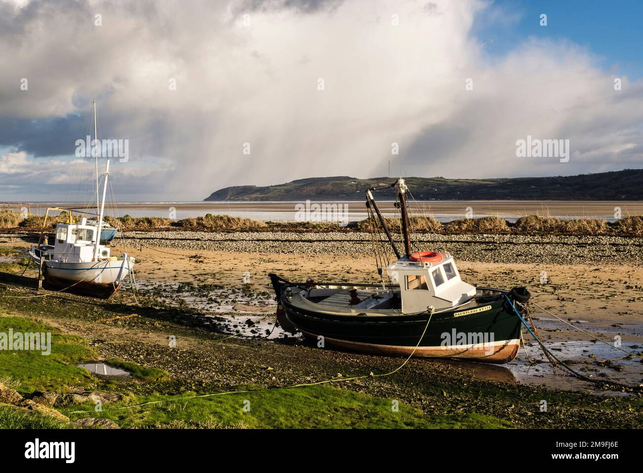 Barche a terra nel porto di Red Wharf Bay, Isola di Anglesey, Galles, Regno Unito, Gran Bretagna, Europa. il promontorio di Llanddona si trova dall'altra parte della baia Foto Stock