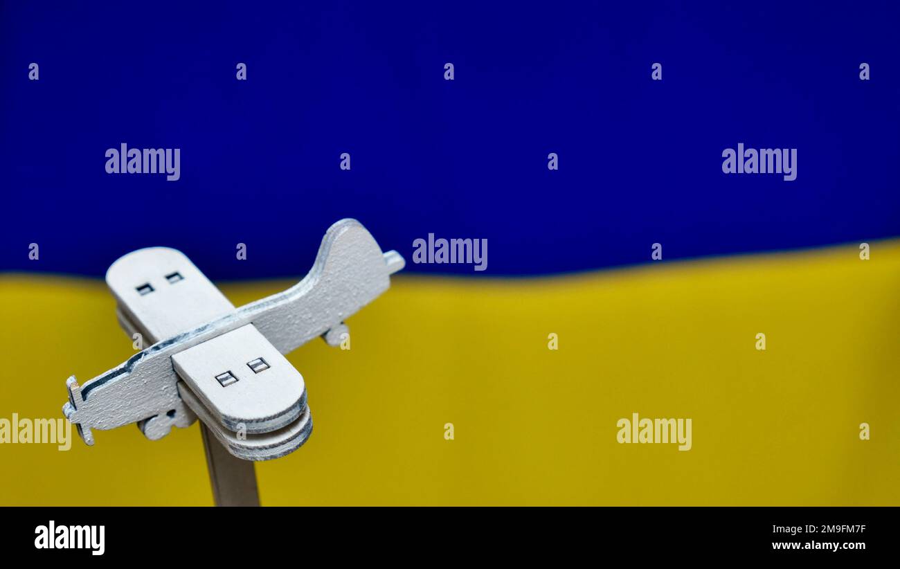 Piano giocattolo decorativo in legno sullo sfondo giallo blu della bandiera Ucraina. La Russia ha attaccato l'Ucraina nel 2022 Foto Stock
