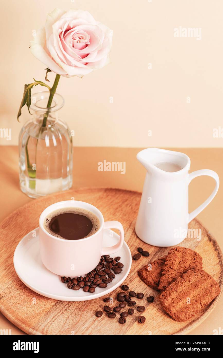 Tazza di caffè, biscotti e caraffa con latte su un vassoio di legno Concetto di colazione mattutina. Foto Stock