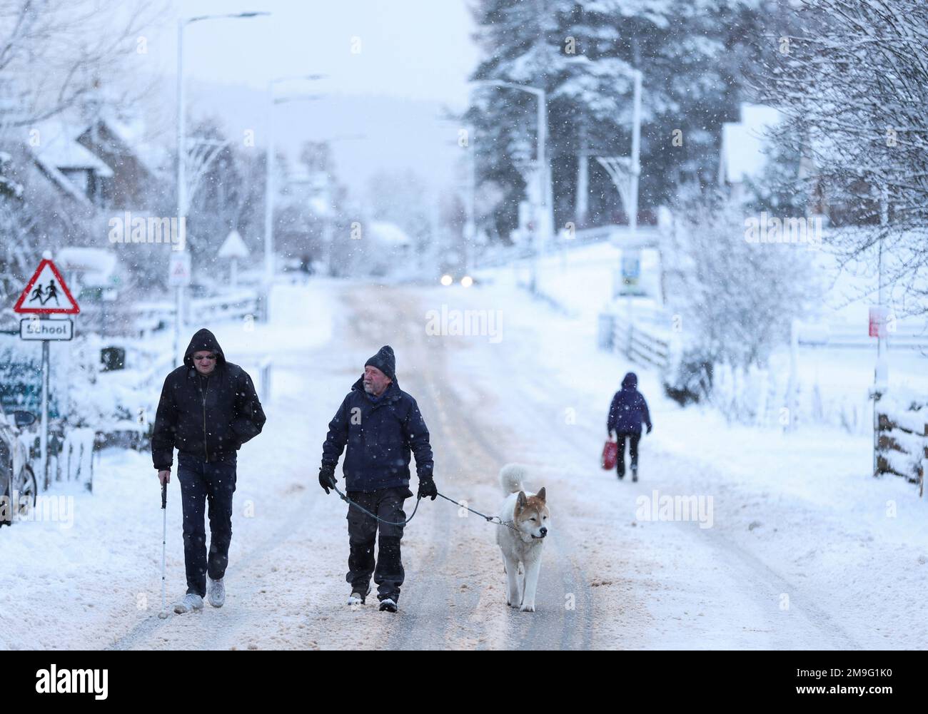 Le persone camminano il loro cane su una strada a Carrbridge, Scozia, Gran Bretagna 18 gennaio 2023. REUTERS/Russell Cheyne Foto Stock