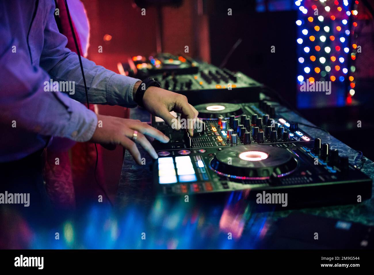 Mani DJ mixare e riprodurre musica su un controller mixer professionale Board in un night club a una festa Foto Stock