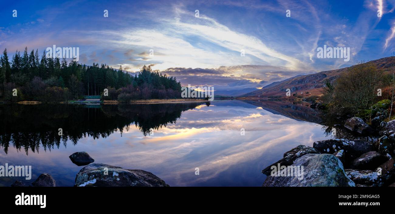 Perfetto riflesso delle montagne e del suggestivo paesaggio nuvoloso in un lago nel Parco Nazionale di Snowdonia, Galles del Nord Foto Stock