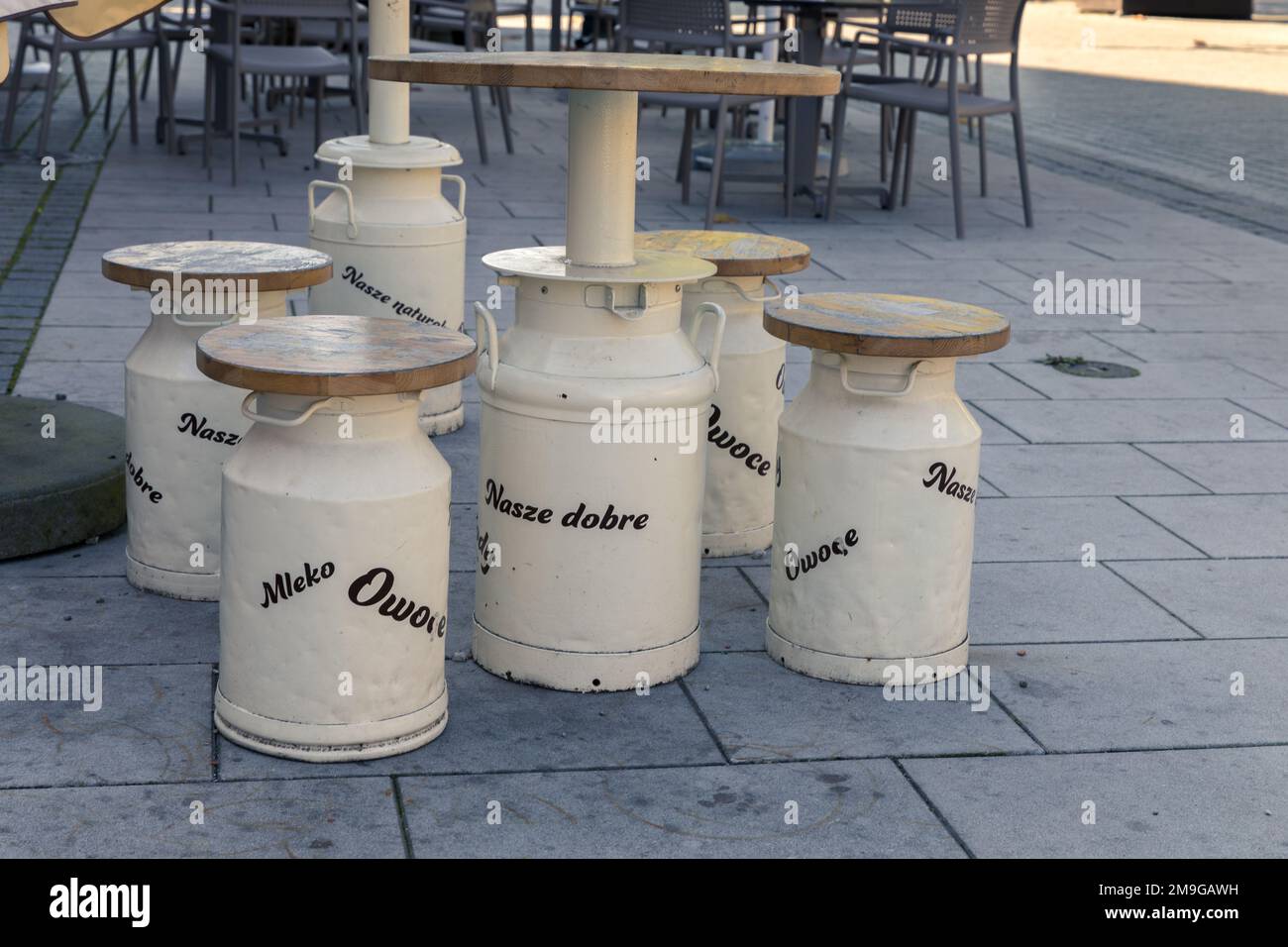 Contenitori di latte bianco convertiti in un tavolo e sedie. Sottotitoli in polacco - il nostro, buono, latte, frutta. Foto Stock
