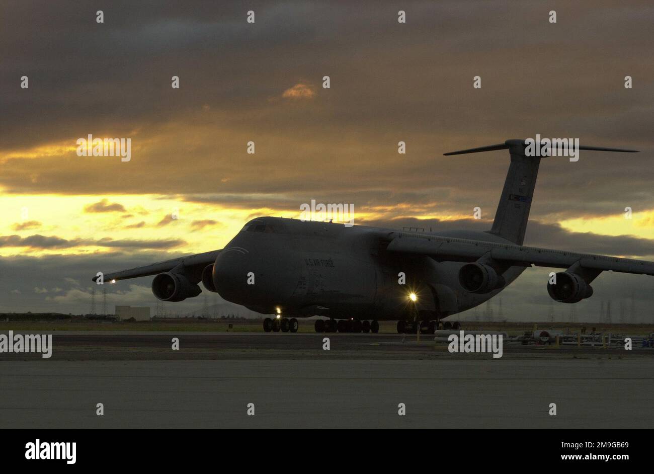 Una galassia C-5B della riserva dell'aeronautica tassa oltre la stazione di rifornimento nella luce di sera al campo d'aviazione federale di Moffett, vista della montagna, California. In grado di contenere 51.150 galloni di carburante, un C-5 con un carico di carico di 270.000 libbre può volare 2.150 miglia nautiche, scaricare, e volare ad una seconda base 500 miglia nautiche di distanza. Base: Moffett Federal Air Field Stato: California (CA) Paese: Stati Uniti d'America (USA) Scene Major Command mostrato: 129th Rescue Wing Foto Stock