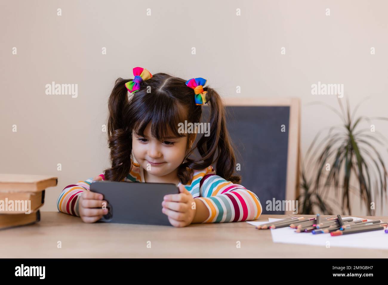 una ragazza piccola cute è agganciata con un insegnante in linea dal telefono. Educazione online dei bambini. Preschoolers e gadget Foto Stock